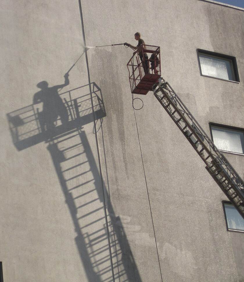 Gevel wordt vanaf een hoogwerker gereinigd met een hogedrukreiniger